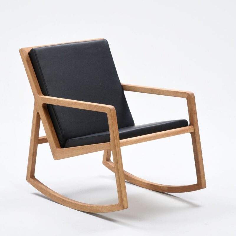Lux keinutuoli, runko öljyttyä tammea, tyynysarja pehmustettu ja verhoiltu mustalla nahalla. Happy home tuote.