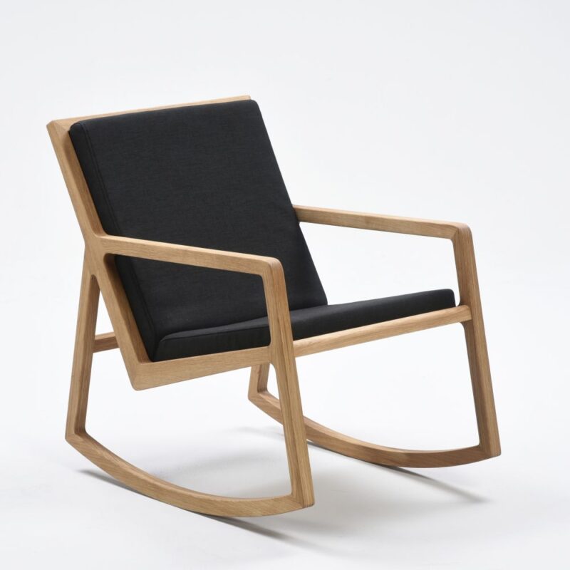 Lux keinutuoli, runko öljyttyä tammea, verhoiltu tumman harmaalla Lido-kankaalla.